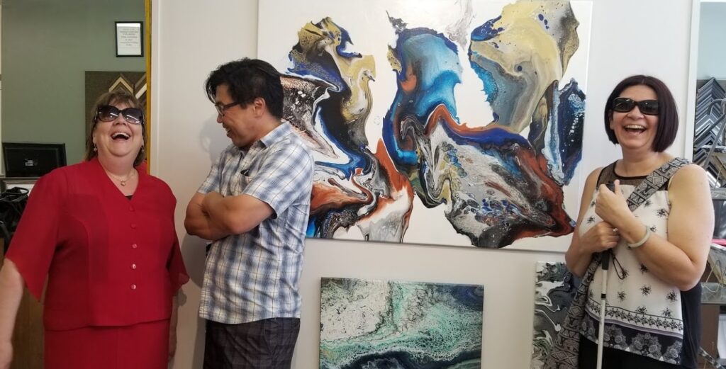 A man and two women standing in front of a large acrylic painting of a dragon