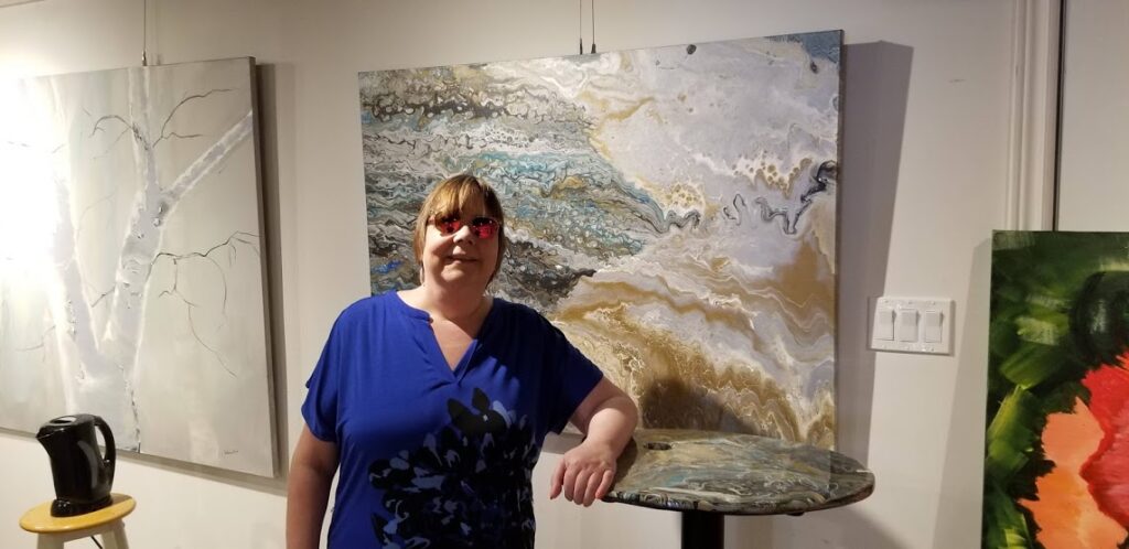 Artist Lynda Todd standing in front of her painting, Mica" hanging at the Cavan Art Gallery. This has been sold.