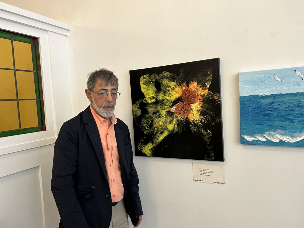 A man standing at a large butterfly artwork at the Quinte Arts Council exhibit in Belleville.