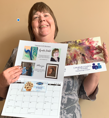 Lynda Todd holding the Canadian Council of the Blind calendar that features her award winning art piece, Blossom, on the front cover.