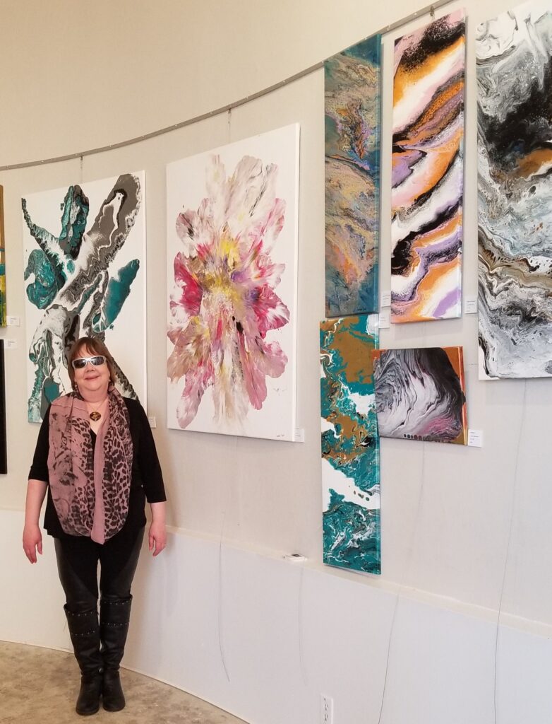 Lynda Todd standing in front her art display at The Mount, Revealing Vibrance.