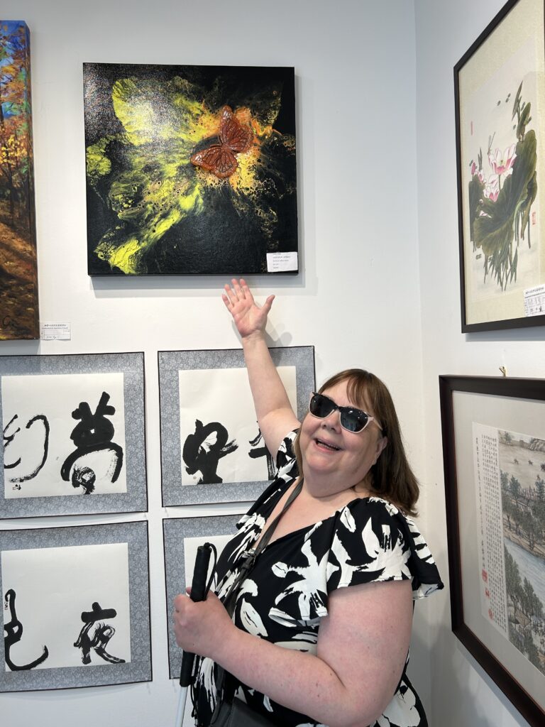 Lynda standing in front of Glistening Butterfly on display at the Chinese Art Exhibit in Scarborough