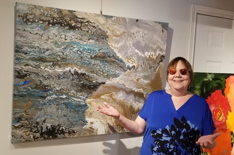 Lynda Todd, Canadian artist standing in front of the painting Sheltered Bay