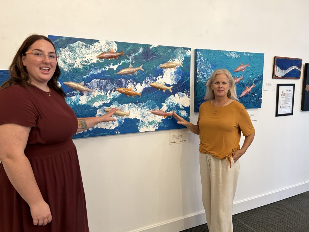 Curators of the Quinte Arts Council gallery standing in front of the art piece Salmon that Lynda Todd created.