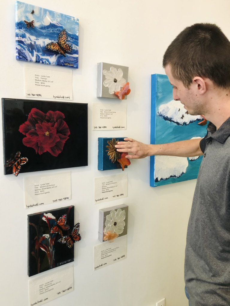 An array of colorful artworks hung on a wall, mostly depicting butterflies and flowers. The top left features a butterfly against a blue and white wave-like background, while below is a large red flower with a butterfly on a dark background. Adjacent smaller pieces depict white flowers with orange butterflies, and another features red flowers with orange butterflies against dark shading. On the right is a snowy landscape with a blue sky. An array of colorful artworks hung on a wall, mostly depicting butterflies and flowers. The top left features a butterfly against a blue and white wave-like background, while below is a large red flower with a butterfly on a dark background. Adjacent smaller pieces depict white flowers with orange butterflies, and another features red flowers with orange butterflies against dark shading. On the right is a snowy landscape with a blue sky. An array of colorful artworks hung on a wall, mostly depicting butterflies and flowers. The top left features a butterfly against a blue and white wave-like background, while below is a large red flower with a butterfly on a dark background. Adjacent smaller pieces depict white flowers with orange butterflies, and another features red flowers with orange butterflies against dark shading. On the right is a snowy landscape with a blue sky. An array of colorful artworks hung on a wall, mostly depicting butterflies and flowers. The top left features a butterfly against a blue and white wave-like background, while below is a large red flower with a butterfly on a dark background. Adjacent smaller pieces depict white flowers with orange butterflies, and another features red flowers with orange butterflies against dark shading. On the right is a snowy landscape with a blue sky.