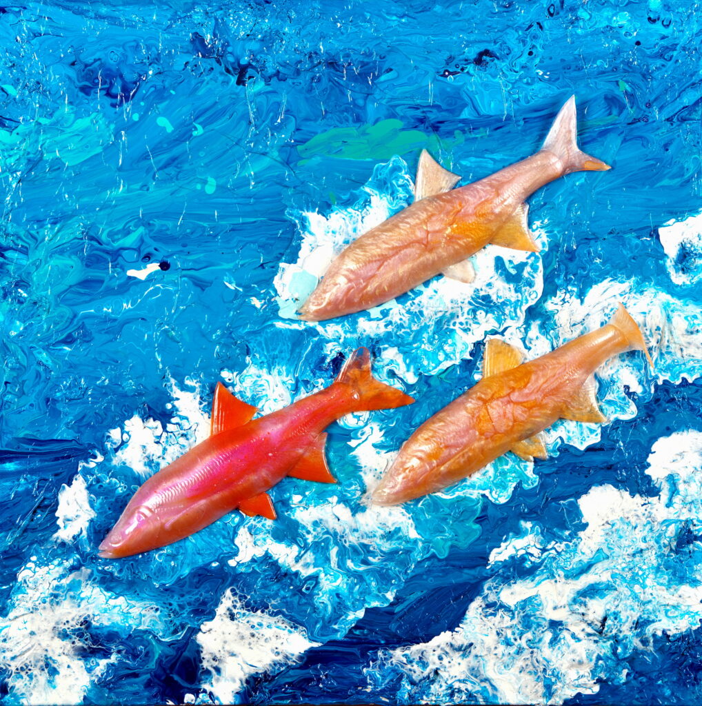 Artwork titled 'Salmon, Salmon, Salmon' showing three large salmon, one painted red and the other two in golden-yellow, swimming through a textured ocean with deep blue waters and frothy white waves. The vivid colors and turbulent backdrop capture the energy and movement of marine life."