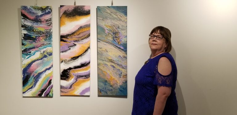 Lynda standing in front three pieces at the Cavan Art Gallerie owned by Valerie Kent.